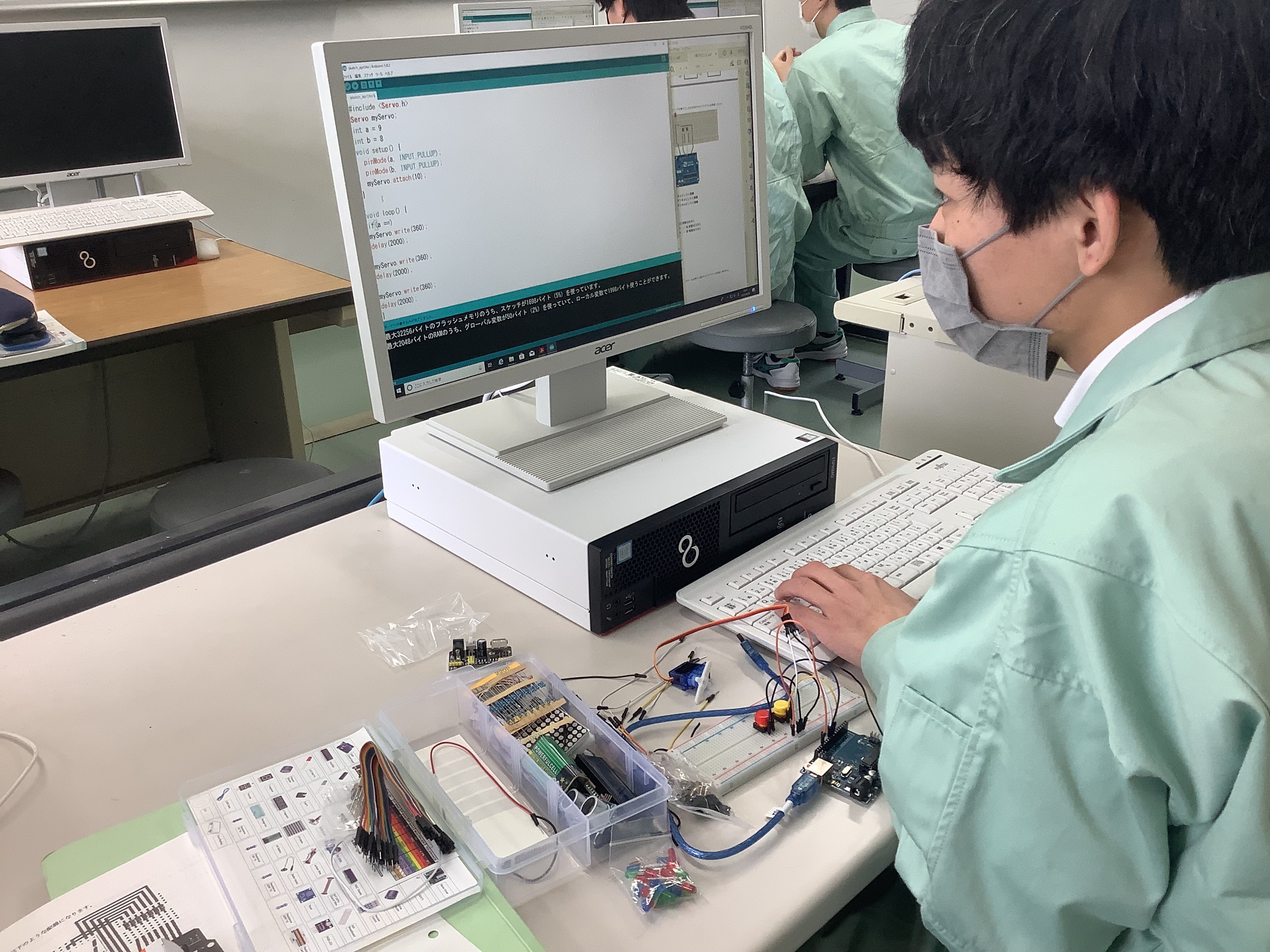 電気情報科の実習でパソコンと電子回路を扱う生徒