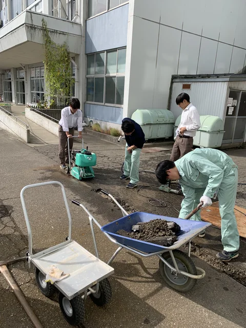 校舎脇で消雪パイプの埋設作業を進める土木防災科の生徒