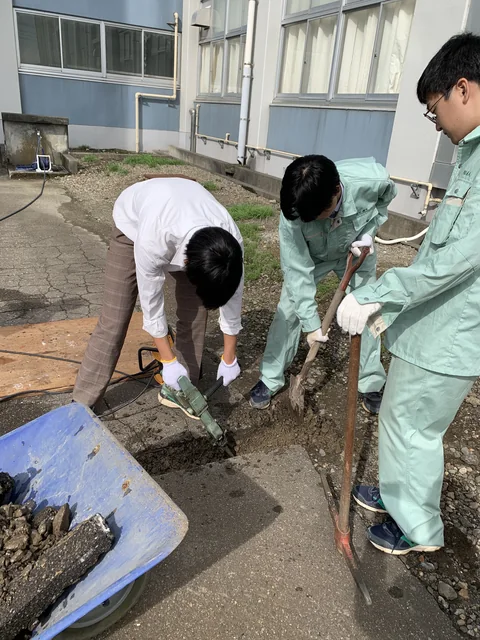 消雪パイプの埋設工事で地面を整える生徒